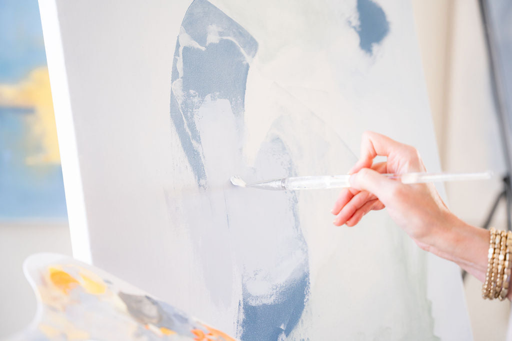 person holding a paint brush against a canvas